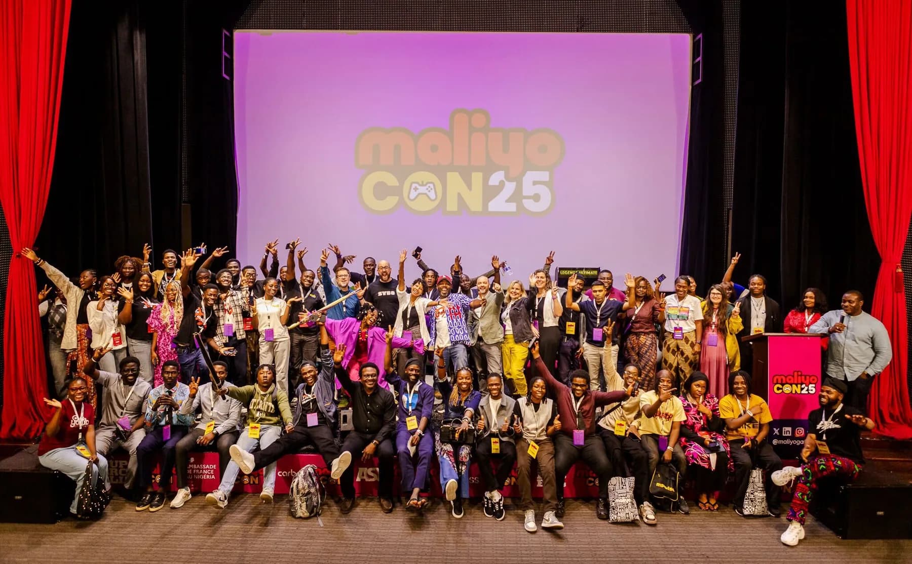 Attendees and speakers cheering in front of the MaliyoCON25 screen